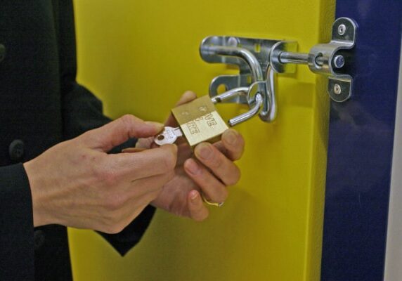 person unlocking padlock on self storage door