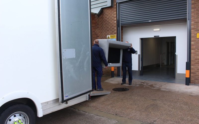 Two men loading a sofa into a self storage unit